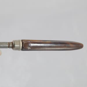 May include: A vintage metal and brown plastic screwdriver with a pointed tip.