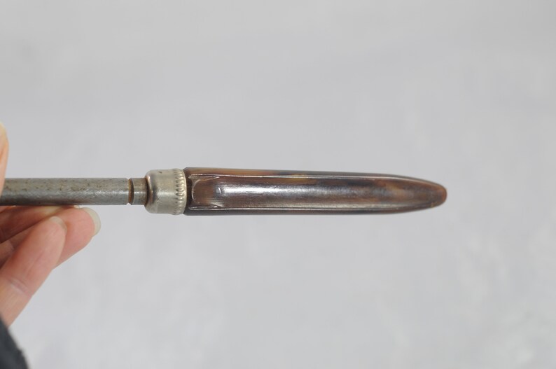 May include: A vintage metal and brown plastic screwdriver with a pointed tip.