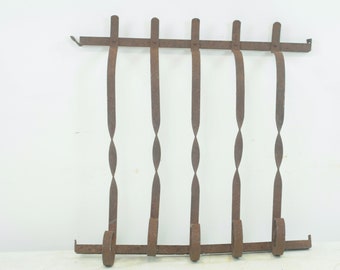 May include: A rusty metal window guard with five vertical bars, each with a twisted design. The bars are connected by a horizontal bar at the top and bottom.