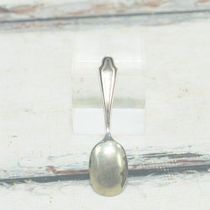 May include: A silver teaspoon with an oval bowl and a simple, elegant design.
