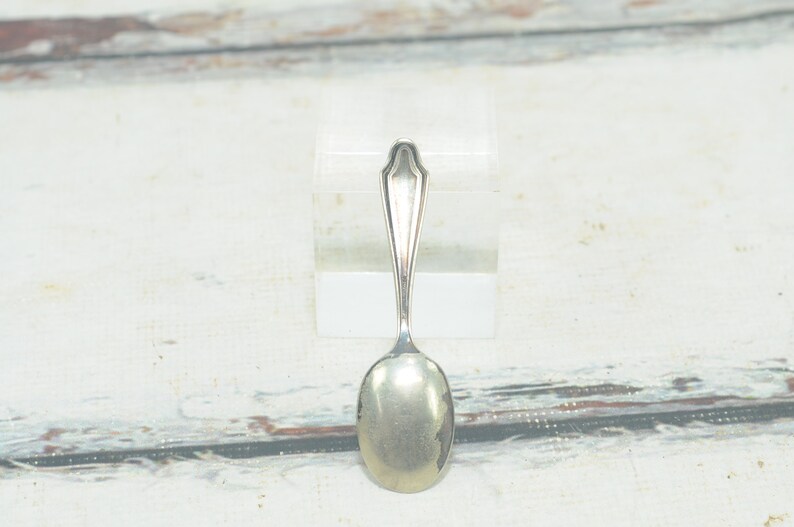 May include: A silver teaspoon with an oval bowl and a simple, elegant design.