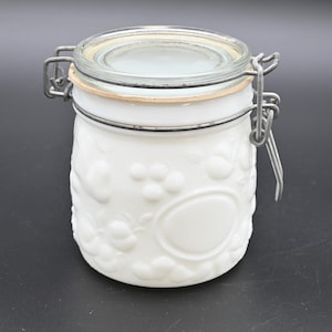 Puede incluir: Tarro de cerámica blanca con tapa de vidrio y cierre de metal. El tarro tiene un diseño floral en relieve.