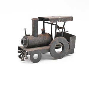 May include: A rusty metal toy train engine with a black paint finish and a single wheel. The engine is made of recycled materials and has a whimsical design.