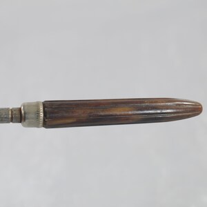 May include: A vintage metal and wood screwdriver with a brown wooden handle. The handle has a ribbed design and a silver metal cap.