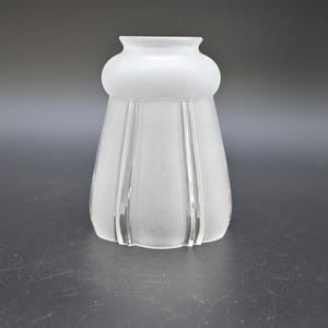 May include: A frosted glass lampshade with a rounded top and a flared, ribbed body. The shade is white and has a classic, vintage design. The lampshade is suitable for a variety of lighting fixtures.