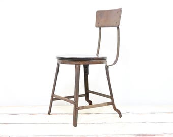 Taburete industrial antiguo de metal con asiento de madera de roble y respaldo.