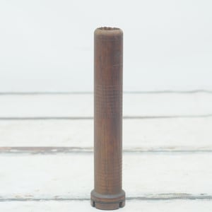 May include: A wooden bobbin with a grooved surface and a rounded base. The bobbin is brown and has a natural wood finish.