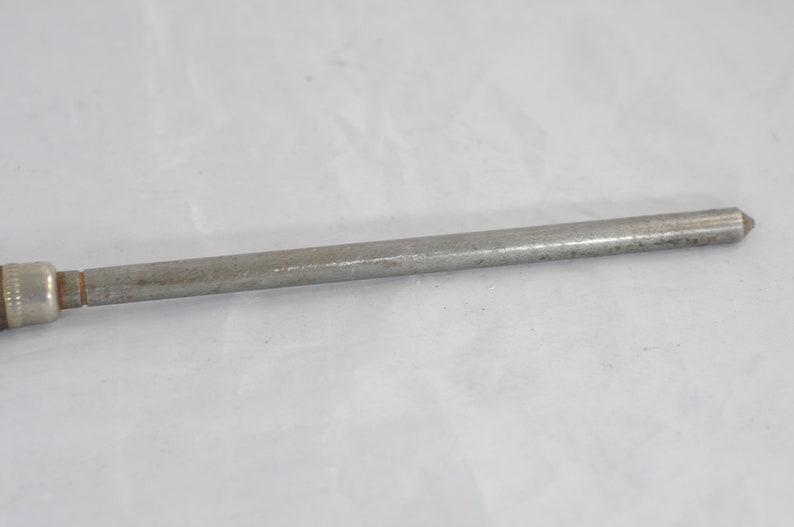 May include: A silver metal tool with a pointed tip and a threaded end. The tool is about 10 inches long.