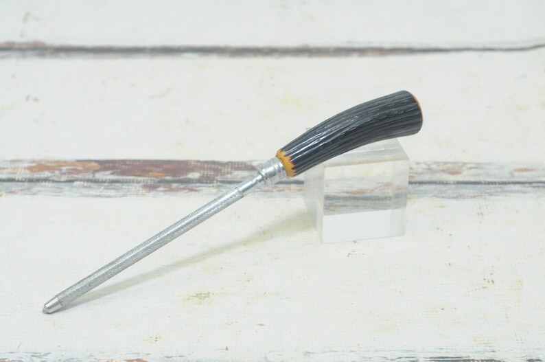 May include: A silver knife sharpener with a black and brown antler handle.