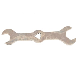 May include: A vintage, double-ended wrench with a central hole. The wrench is made of metal with a worn, rusty appearance. The size marking "5/8" is visible on the tool. The tool is designed for tightening or loosening nuts and bolts.
