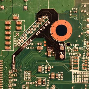 May include: Close-up of a green circuit board with various electronic components. A black and orange component is labelled "Slim PLL OSB" and "POST PLL". Other labels include "Element18592" and "FT5R17".