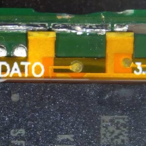 Puede incluir: Primer plano de una placa de circuito verde con componentes amarillos y naranjas. Los textos "DATO" y "3.3V" son visibles en blanco. La placa tiene un componente rectangular gris oscuro en la parte inferior.