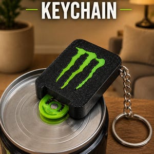 May include: A black rectangular can opener keychain featuring a bright green claw logo on the top surface. The device is positioned on the silver lid of a beverage can, with a metal chain and ring attached to the side. Text reads CAN OPENER KEYCHAIN.