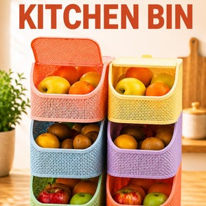 May include: A stack of six rectangular plastic storage bins with a textured grid pattern, arranged in two columns. The bins are colored peach, yellow, blue, purple, green, and orange, each containing various fresh fruits like apples and oranges.