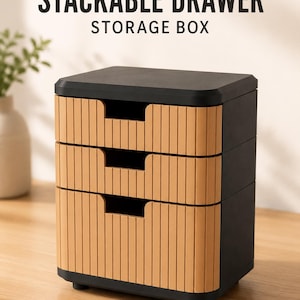 May include: A stackable drawer storage box with a black frame and three light brown drawers. Each drawer features a vertical ribbed texture and a central cutout handle. The text STACKABLE DRAWER STORAGE BOX is printed in black above the unit.
