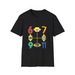 Può includere: Una t-shirt nera a maniche corte con una stampa grafica raffigurante una griglia con i numeri 6, 7, 9 e 11 in vari colori. La griglia include frecce gialle e piccole icone quadrate con un'emoji che ride e un logo 7-Eleven.