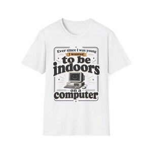 May include: A white short-sleeved t-shirt featuring a graphic print with the text "Ever since I was young I wanted to be indoors on a computer" in black and tan lettering, centred above an illustration of a vintage desktop computer.