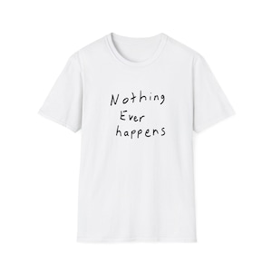 May include: A white short-sleeved t-shirt featuring the black handwritten-style text Nothing Ever happens centered on the chest. The garment has a crew neckline and a standard fit, constructed from a plain white fabric with a simple design.