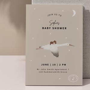 May include: A baby shower invitation with a beige background. The invitation features the text "Join us to Sophies BABY SHOWER" and the date "June 10 | 2 PM". A stork carrying a baby is illustrated on the invitation.