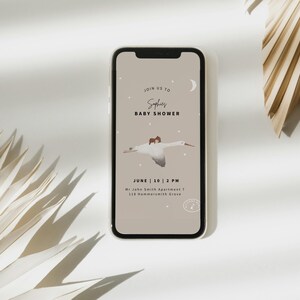 May include: A smartphone displays a baby shower invitation. The invitation features the text "Join us to Sophie's Baby Shower" with a graphic of a stork carrying a baby. The date and time are also included.