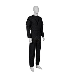 Pode incluir: Um conjunto de uniforme preto de duas pe&ccedil;as composto por uma blusa de manga curta com remendos retangulares no peito e ombros, e cal&ccedil;as compridas a condizer com detalhes de acolchoamento horizontal na zona das coxas, num manequim.