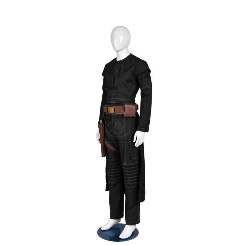 Puede incluir: Un conjunto de camisa de manga larga y pantal&oacute;n negro con paneles acanalados reforzados en hombros y rodillas. El atuendo incluye un cintur&oacute;n utilitario de cuero marr&oacute;n con una funda y un peque&ntilde;o bolsillo, acentuado con costuras blancas.