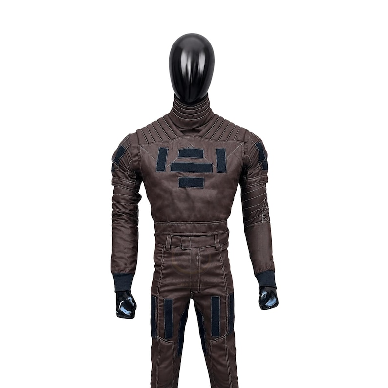 May include: A dark brown long-sleeved jumpsuit featuring a high ribbed collar, padded shoulder detailing, and black rectangular patches on the chest and thighs. The garment includes fitted cuffs and structured stitching throughout the torso and legs.