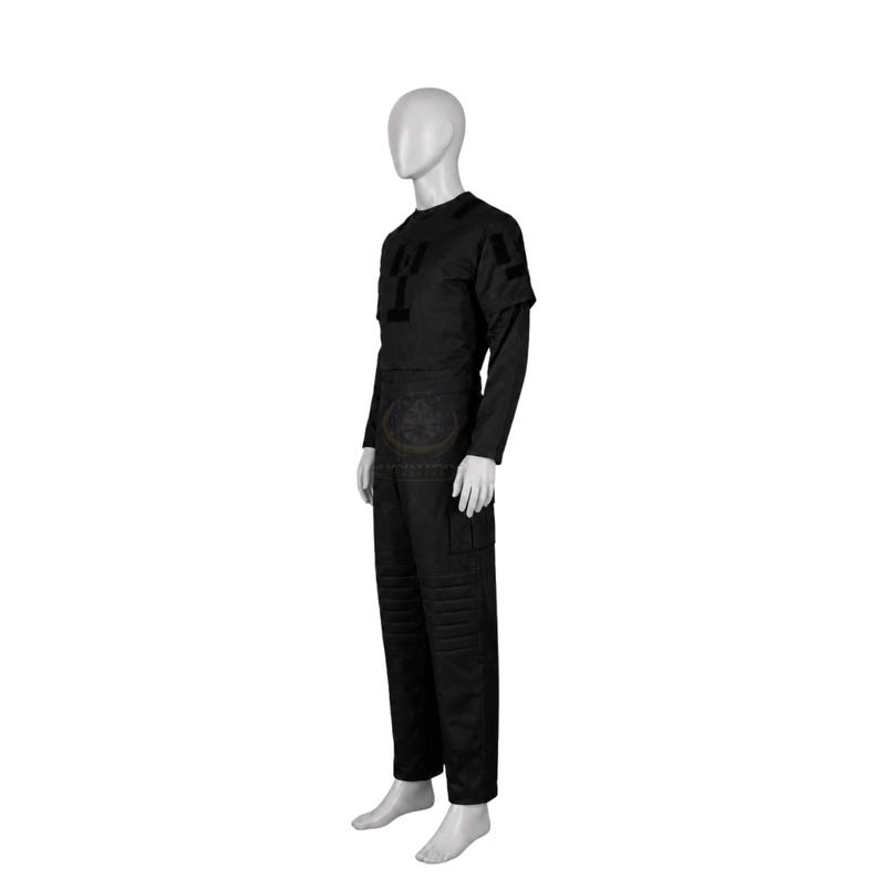 Pode incluir: Um conjunto de uniforme t&aacute;tico preto composto por uma camisa de manga comprida e cal&ccedil;as a condizer num manequim. A camisa apresenta um emblema retangular no peito e um emblema na manga. As cal&ccedil;as incluem joelhos refor&ccedil;ados e bolsos laterais.