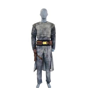 May include: A gray costume displayed on a mannequin. The outfit includes a long-sleeved top, pants, and a belt with ammunition. A holster with a gun is attached to the belt. The costume has a weathered appearance, suggesting a vintage or battle-worn aesthetic.