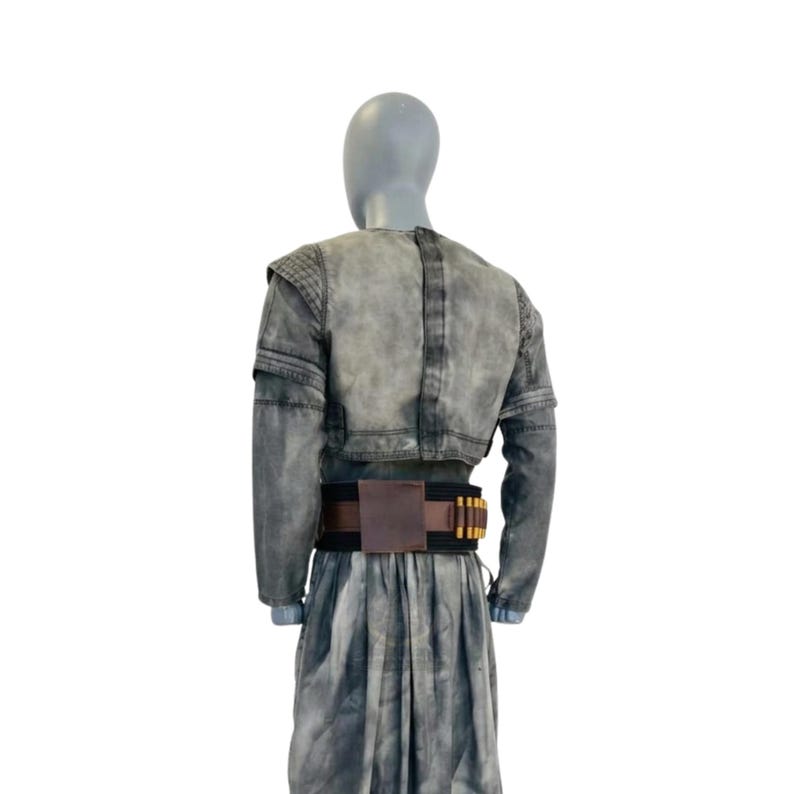 May include: A gray denim jacket with long sleeves and a cropped waist, paired with a matching skirt. A brown leather belt with gold-colored accents is worn at the waist. The outfit is displayed on a mannequin.