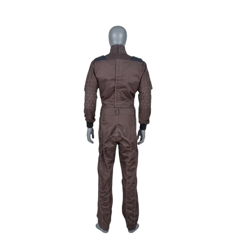 May include: Brown jumpsuit with black shoulder and sleeve accents. The jumpsuit features a high collar and a zip closure. Decorative stitching adorns the sleeves. The garment is displayed on a mannequin.