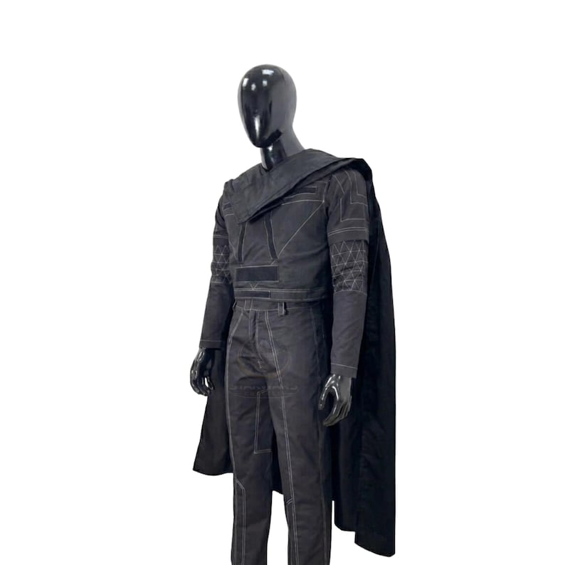 May include: A black long-sleeved top and matching trousers set featuring white contrast stitching, geometric patterns on the sleeves, and a structured shoulder overlay. The outfit is completed by a long, flowing black cape worn over the shoulders.