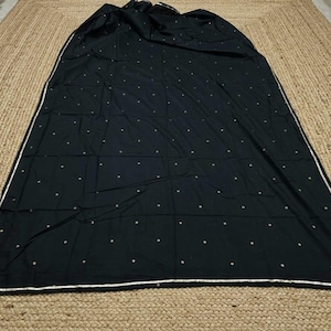 May include: A black rectangular fabric piece featuring a repeating pattern of small gold-colored dots across the surface. The edges are finished with a thin, metallic gold border that frames the entire perimeter of the textile item.