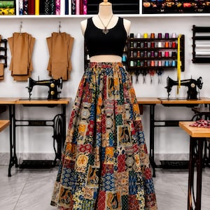 May include: A black sleeveless crop top paired with a floor-length, high-waisted skirt featuring a multi-colored patchwork pattern of various geometric and animal motifs in shades of red, blue, yellow, and green on a mannequin.