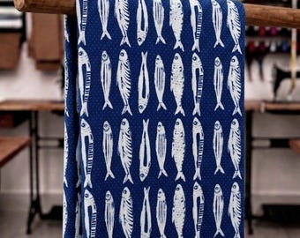 Puede incluir: Una tela de color azul profundo con un patrón repetitivo de ilustraciones de peces blancos. Los peces están dispuestos en filas verticales, cada uno representado con un detallado trabajo de líneas. El fondo tiene una textura de puntos blancos.
