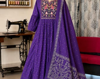 Puede incluir: Un vestido de color morado intenso con mangas largas, cintura fruncida y dupatta a juego. El corpiño presenta un intrincado bordado floral y de aves multicolor alrededor del escote. La tela tiene un pequeño patrón blanco repetido.