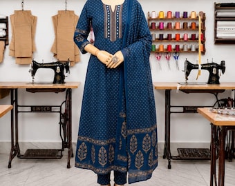 May include: A dark blue three-piece outfit on a mannequin, featuring a long-sleeved kurta with a gold geometric pattern, a matching dupatta draped over the shoulder, and slim-fit trousers, paired with beige flat shoes on the floor.