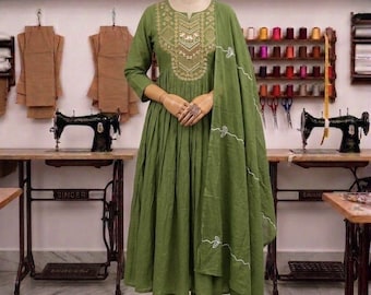 May include: An olive green long-sleeved dress with a pleated skirt and gold embroidery around the neckline. The outfit includes matching olive green trousers and a coordinating olive green dupatta featuring white embroidered floral vine details.