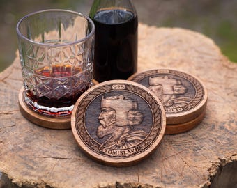 May include: Round wooden coasters featuring a carved profile of a king wearing a crown, with the text "TOMISLAV" and "925" engraved on the surface. The coasters have a braided border design and are shown with a glass of dark liquid and a bottle.