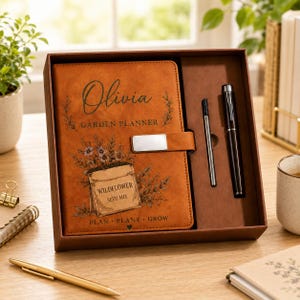 May include: A tan garden planner notebook with the name Olivia, a wildflower seed mix illustration, and the text Plan Plant Grow, featuring a silver magnetic closure, presented in a gift box with a black pen and a thin metal stylus.