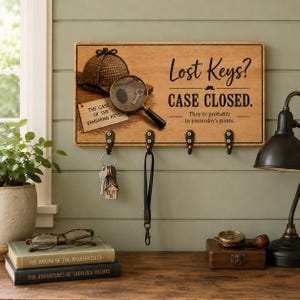 May include: A rectangular wooden wall-mounted key holder featuring a graphic of a deerstalker hat, a magnifying glass, and a note labeled The Case of the Vanishing Keys. Text reads Lost Keys? CASE CLOSED. They're probably in yesterday's pants.