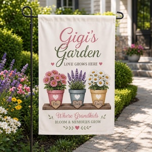 May include: A cream-colored garden flag featuring the text 'Gigi's Garden LOVE GROWS HERE' and 'Where Grandkids BLOOM & MEMORIES GROW'. It displays three potted plants with heart-shaped tags labeled 'Ella', 'Jack', and 'Lucy' on a wooden shelf.