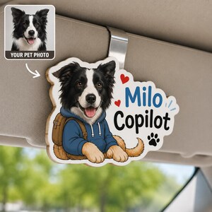 May include: A custom car visor clip featuring a cartoon illustration of a black and white Border Collie wearing a blue hoodie and a brown backpack. The text reads Milo Copilot, accompanied by two red hearts and a black paw print icon.