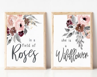 May include: Two framed prints with watercolor floral designs. The left print features a bouquet of pink, burgundy, and gray flowers with the text "in a field of Roses". The right print features a bouquet of pink, burgundy, and gray flowers with the text "she is a Wildflower".