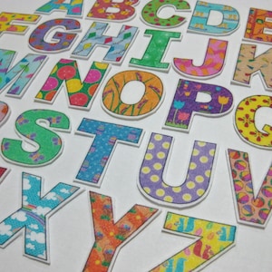 May include: A collection of colorful, patterned alphabet letters. Each letter is a different color and design, including floral, fruit, and geometric patterns. The letters are cut out and have a white border, perfect for crafts or educational projects.