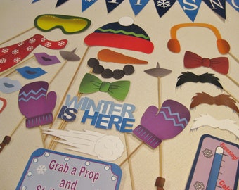 May include: A set of winter-themed photo booth props, including a snowman, mittens, a carrot nose, a mustache, a scarf, and a sign that says "Winter is Here".