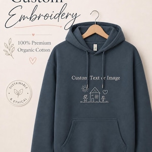 Könnte beinhalten: Ein dunkelblauer Kapuzenpullover mit Kängurutasche und passenden Kordelzügen. Auf der Brust steht der Text "Custom Text or Image" über einer Strichzeichnung eines Hauses, einer Sonne, eines Herzens und zweier Figuren. Ein rundes Abzeichen trägt die Aufschrift "Sustainable & Ethical".