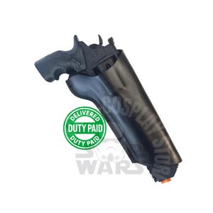 May include: A black holster containing a black pistol with a textured grip featuring a wing design. The pistol has a small orange tip at the barrel end. A green circular logo with the text DELIVERED DUTY PAID is visible on the holster surface.