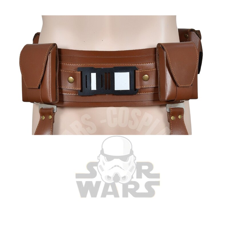 May include: A brown leather belt with two pouches and a central buckle. The belt has a rectangular black and white buckle and is secured with suspender-style straps. The belt is designed to be worn around the waist.