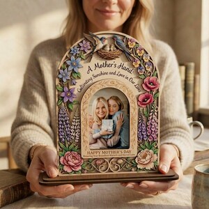 Może przedstawiać: Drewniana ramka na zdjęcia na Dzień Matki z kwiatowymi i ptasimi detalami. Ramka zawiera tekst "A Mother's Hand: Cultivating Sunshine and Love in Our Lives" i "Happy Mother's Day". Zawiera zdjęcie dwóch kobiet.